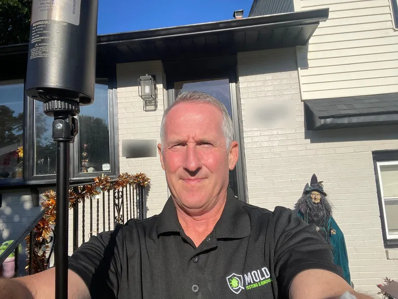 Mold Testing and Removal inspector in a branded uniform on site with an air sampling pump before a mold test in Philadelphia